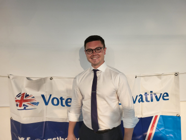 Freddie Downing standing in front of a banner that says "Vote Conservative"